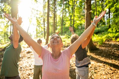 Frau beim Waldbaden blickt in die Sonne